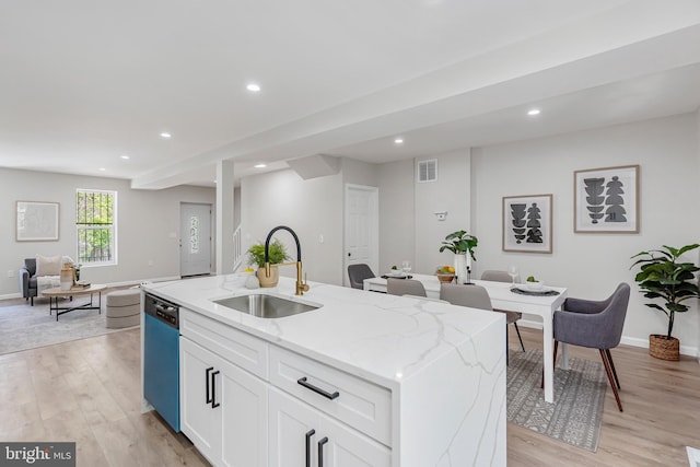 kitchen featuring visible vents, open floor plan, light stone counters, a sink, and dishwasher