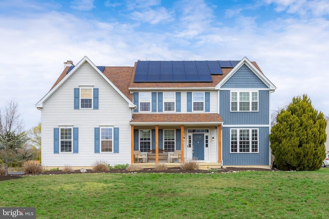 traditional-style house featuring covered porch, solar panels, a front lawn, a shingled roof, and a chimney