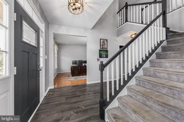 foyer with stairs, wood finished floors, baseboards, and a chandelier