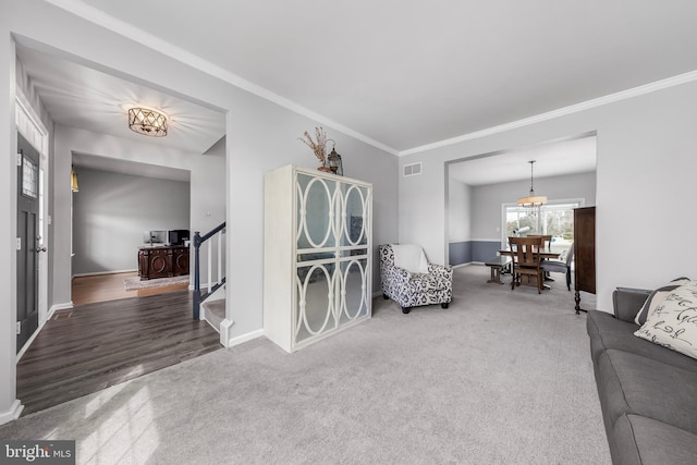 living room with carpet, ornamental molding, baseboards, and stairs