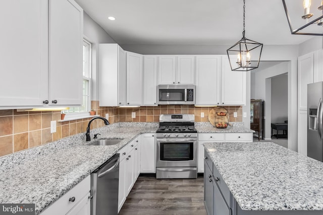 kitchen featuring stainless steel appliances, a sink, a chandelier, white cabinets, and dark wood finished floors