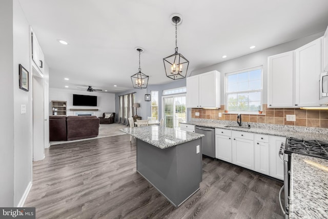 kitchen with stainless steel appliances, a sink, recessed lighting, open floor plan, and decorative backsplash