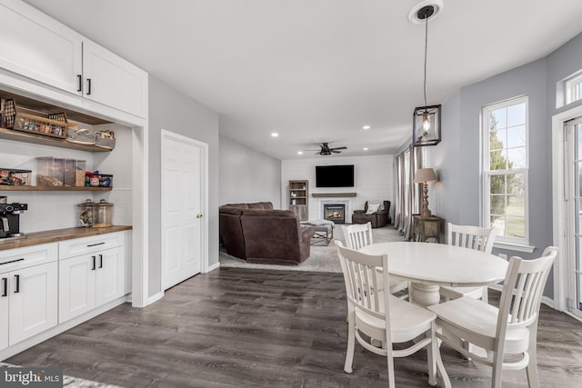 dining area featuring a glass covered fireplace, recessed lighting, dark wood-style floors, ceiling fan, and baseboards