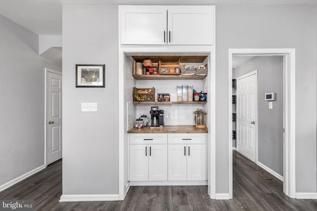 indoor dry bar featuring dark wood-style flooring, baseboards, and backsplash