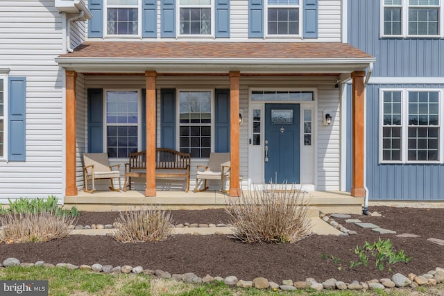 property entrance featuring covered porch and roof with shingles