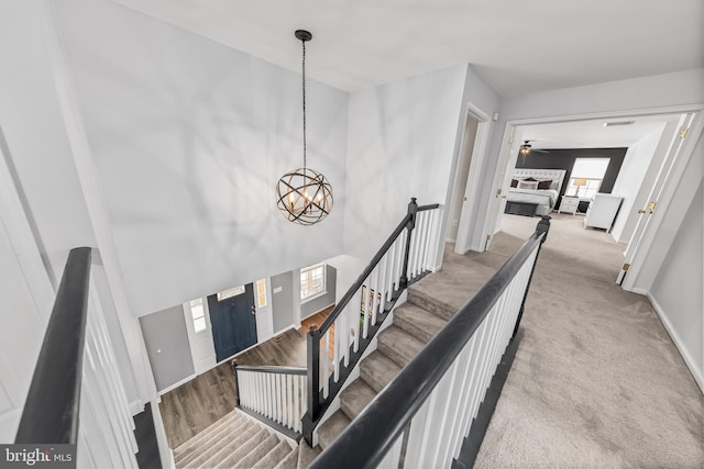 stairway with a chandelier, baseboards, carpet, and a ceiling fan