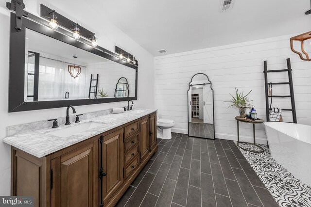 bathroom featuring double vanity, a soaking tub, toilet, and wood walls