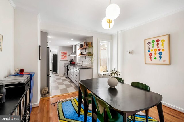 dining room featuring light wood-type flooring, crown molding, baseboards, and recessed lighting