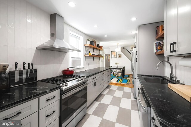 kitchen with wall chimney range hood, open shelves, appliances with stainless steel finishes, light floors, and recessed lighting