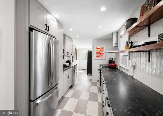 kitchen with appliances with stainless steel finishes, open shelves, wall chimney exhaust hood, dark countertops, and recessed lighting