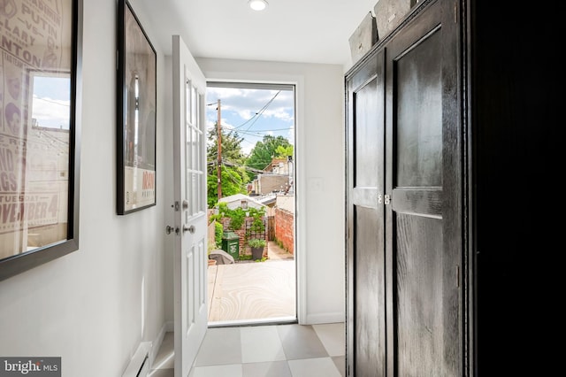 doorway with baseboards, light floors, and recessed lighting