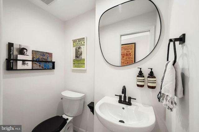 half bath with a sink, toilet, and baseboards