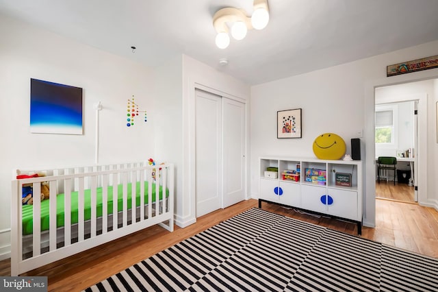 bedroom with wood finished floors, a closet, and baseboards