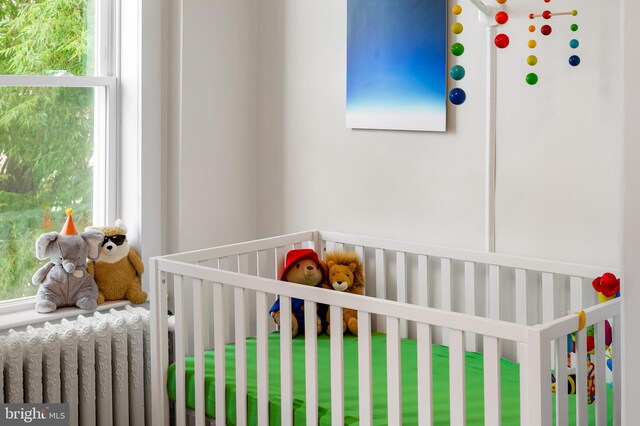 bedroom featuring radiator heating unit and a nursery area