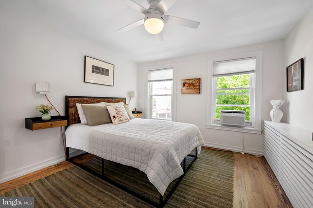 bedroom featuring wood finished floors, baseboards, cooling unit, and a ceiling fan