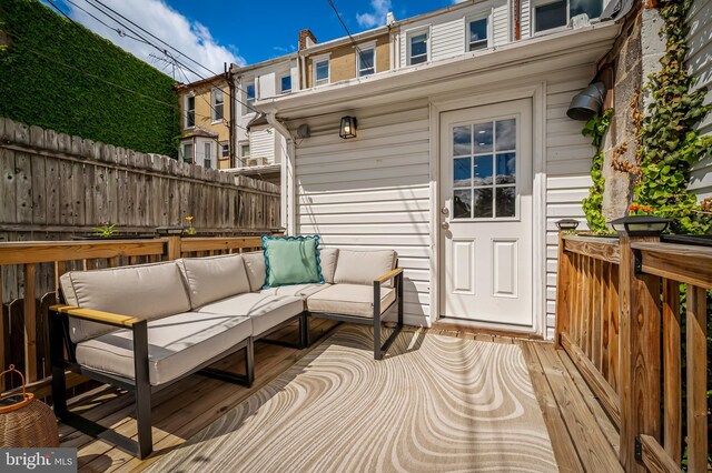 wooden terrace with outdoor lounge area and fence