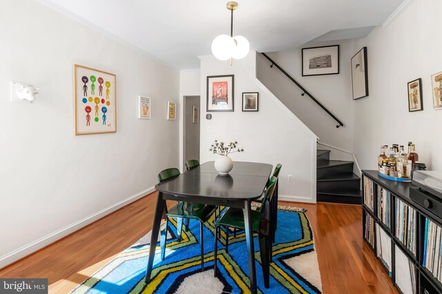 dining area with stairs, wood finished floors, baseboards, and crown molding