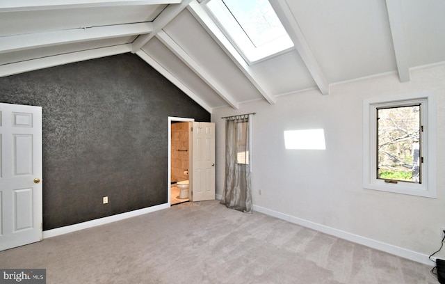 unfurnished bedroom with baseboards, lofted ceiling with skylight, ensuite bath, and light colored carpet