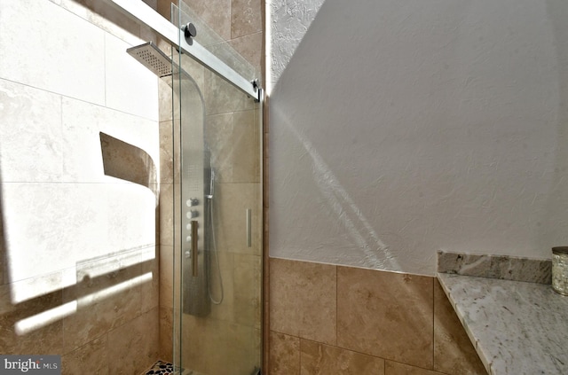 interior details with a textured wall and a stall shower