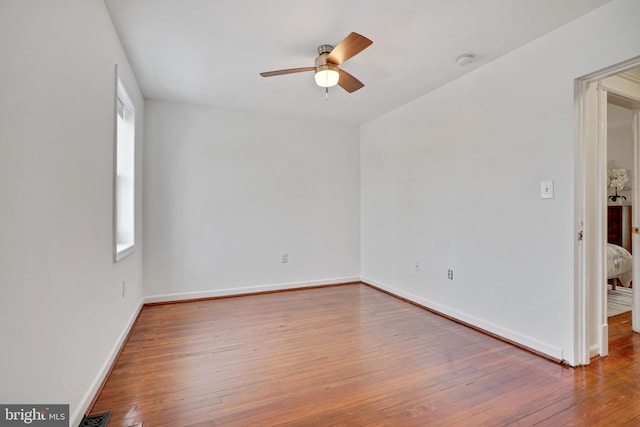 spare room featuring a healthy amount of sunlight, baseboards, a ceiling fan, and hardwood / wood-style flooring