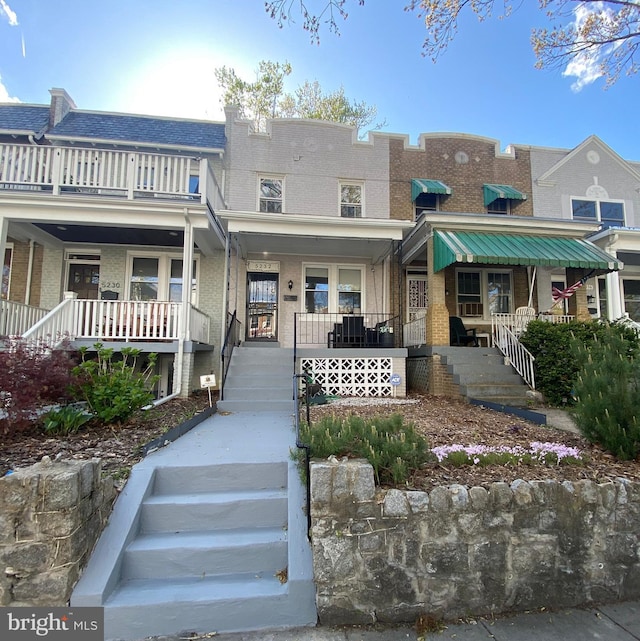 multi unit property with brick siding, covered porch, and stairway