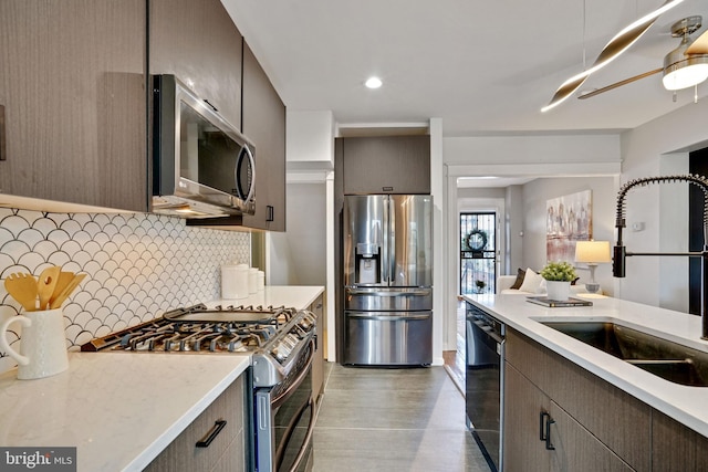 kitchen with tasteful backsplash, wood finished floors, a sink, stainless steel appliances, and recessed lighting