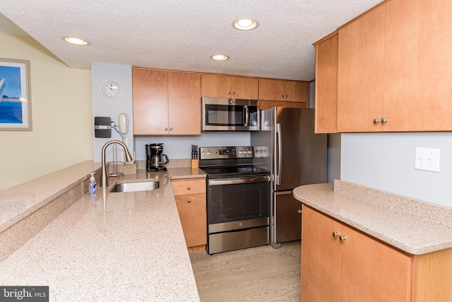 11500 Coastal Hwy Unit 317, Ocean City, MD 21842 - kitchen with a sink, appliances with stainless steel finishes, a peninsula, a textured ceiling, and light wood-style flooring