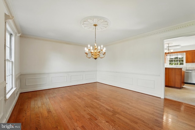 unfurnished dining area with wainscoting, wood-type flooring, and a notable chandelier