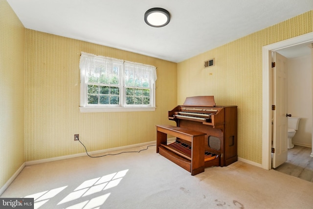 living area featuring carpet flooring, baseboards, wallpapered walls, and visible vents