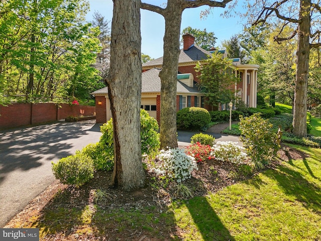 view of property exterior with a chimney, fence, an attached garage, a shingled roof, and aphalt driveway
