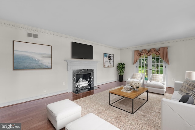 living area with a fireplace, wood finished floors, visible vents, and ornamental molding