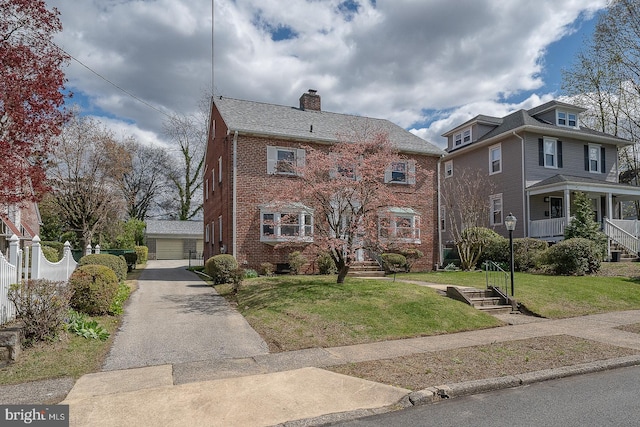 view of front of home featuring a chimney, brick siding, a garage, and a front yard