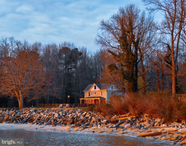 exterior space with a water view, a view of trees, and fence