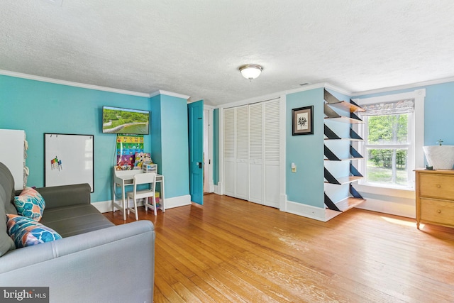 living room with visible vents, baseboards, ornamental molding, a textured ceiling, and wood finished floors