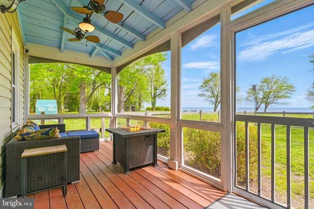 sunroom / solarium featuring beamed ceiling, ceiling fan, a water view, and an outdoor fire pit