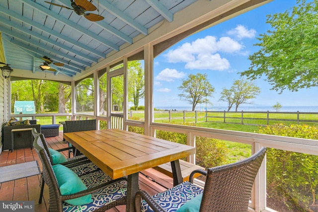 sunroom featuring beam ceiling, outdoor dining space, ceiling fan, and a water view