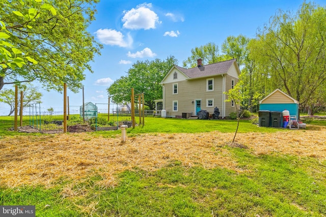 back of property featuring an outdoor structure, a lawn, and a garden