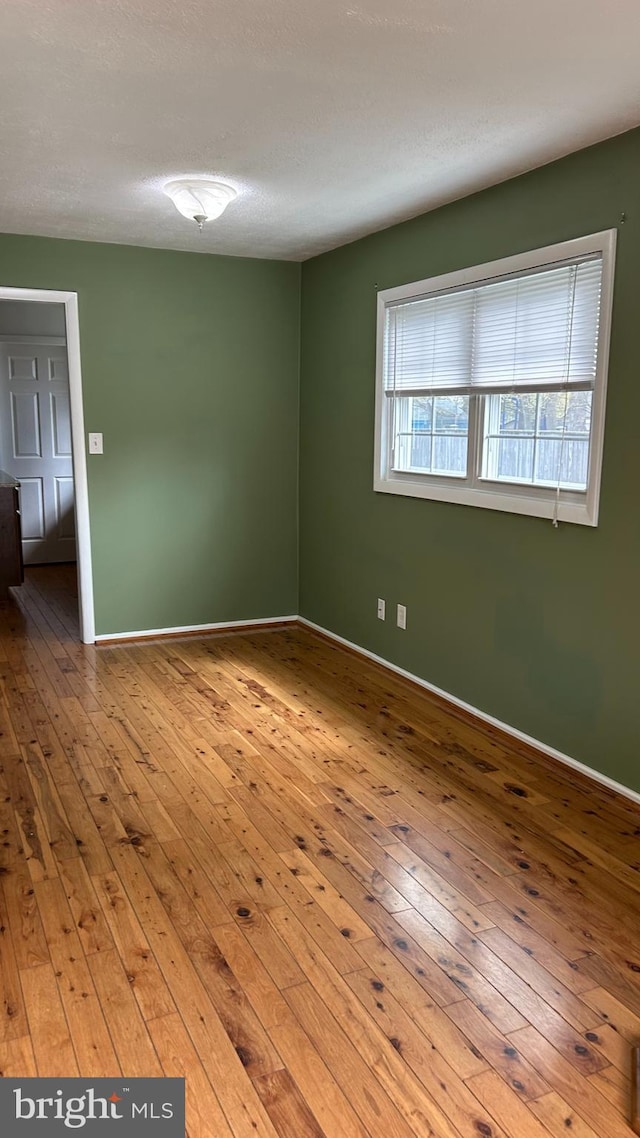 empty room featuring wood-type flooring and baseboards