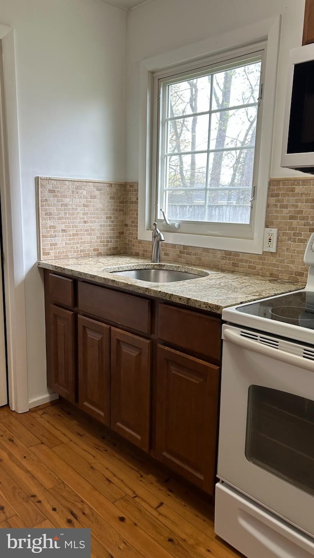 kitchen featuring tasteful backsplash, a sink, white appliances, and light wood-type flooring