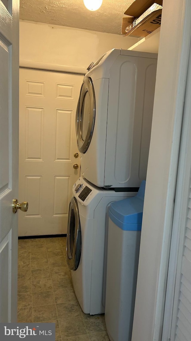 washroom featuring laundry area, a textured ceiling, and stacked washer and clothes dryer