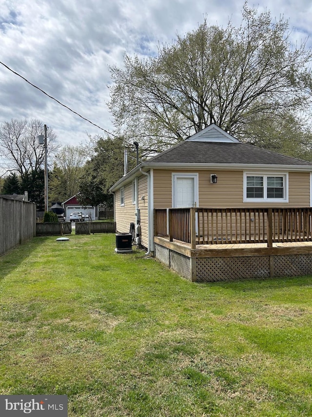 back of property featuring a wooden deck, fence, and a lawn