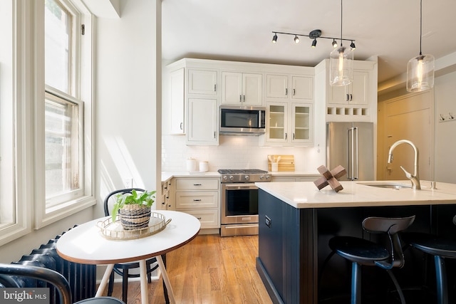 kitchen featuring plenty of natural light, a sink, appliances with stainless steel finishes, and a kitchen bar