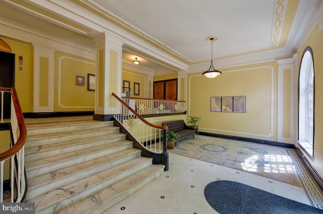 entryway featuring crown molding, stairs, and a decorative wall