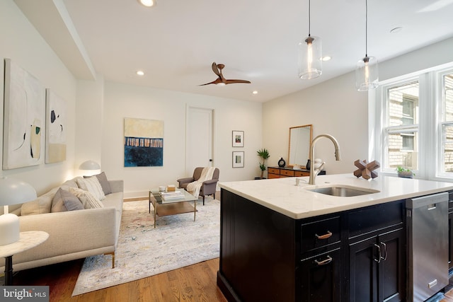 kitchen featuring dark cabinets, a sink, dishwasher, and open floor plan