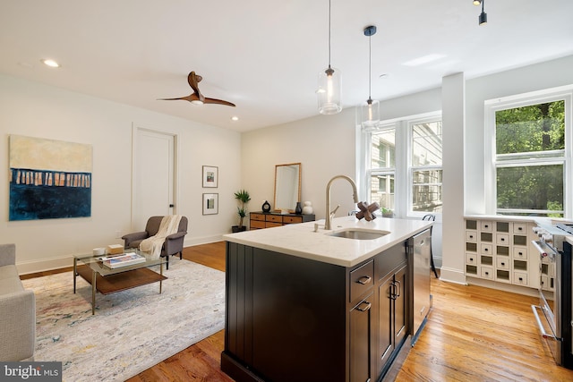 kitchen with decorative light fixtures, open floor plan, a sink, and light wood-type flooring