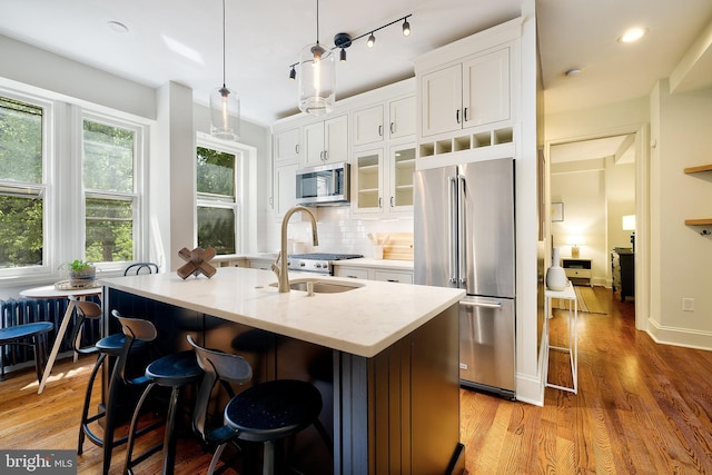 kitchen with light wood finished floors, an island with sink, white cabinets, and stainless steel appliances