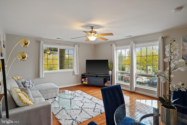 living area featuring a healthy amount of sunlight, wood finished floors, and a ceiling fan