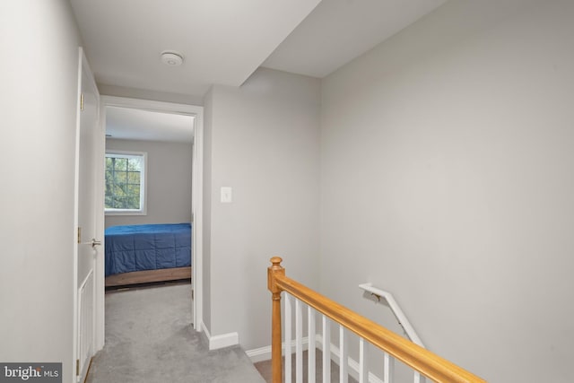 hall with baseboards, an upstairs landing, and carpet