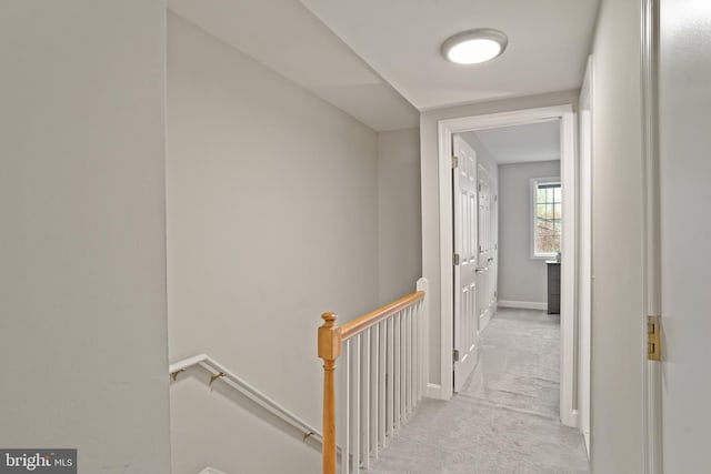 corridor with baseboards, an upstairs landing, and light colored carpet