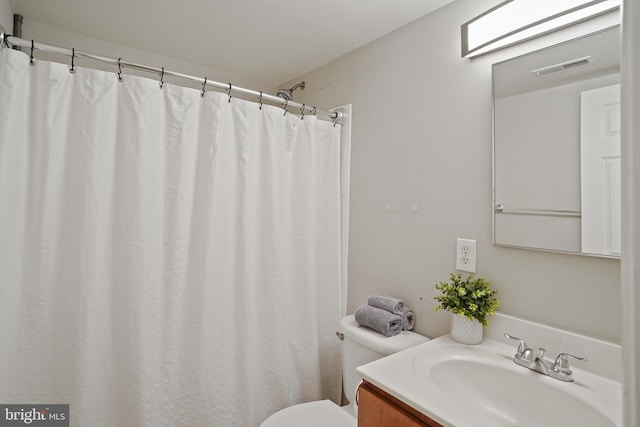 bathroom with a shower with shower curtain, vanity, visible vents, and toilet